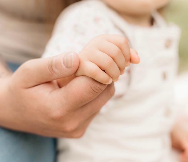 Babyhand umfasst den Finger eines Elternteils