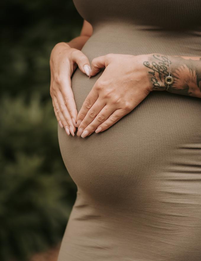 Hände formen ein Herz auf einem Babybauch