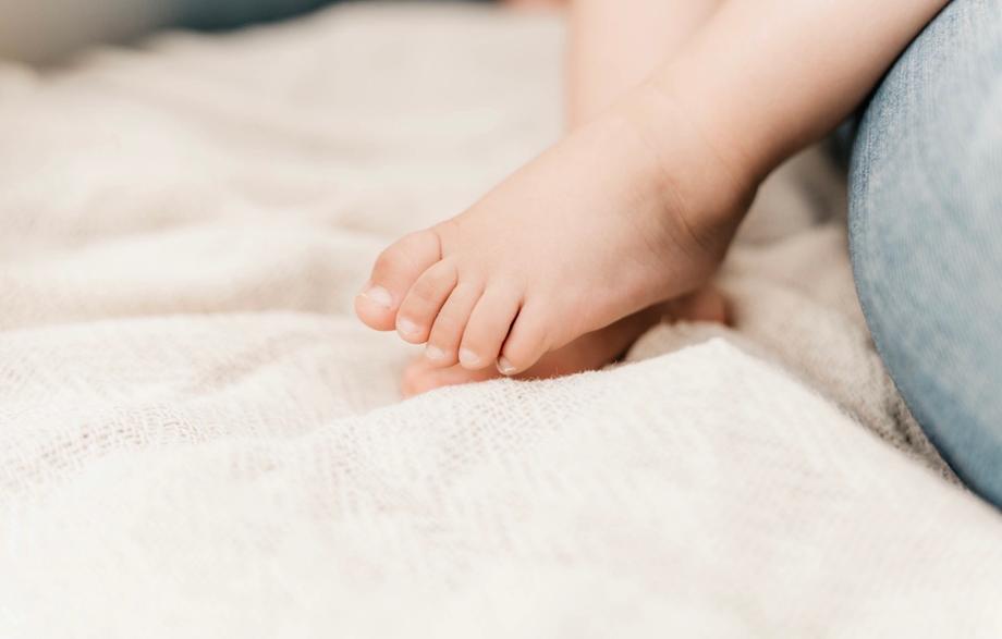 Kleine Babyfüße auf einer weichen, hellen Decke