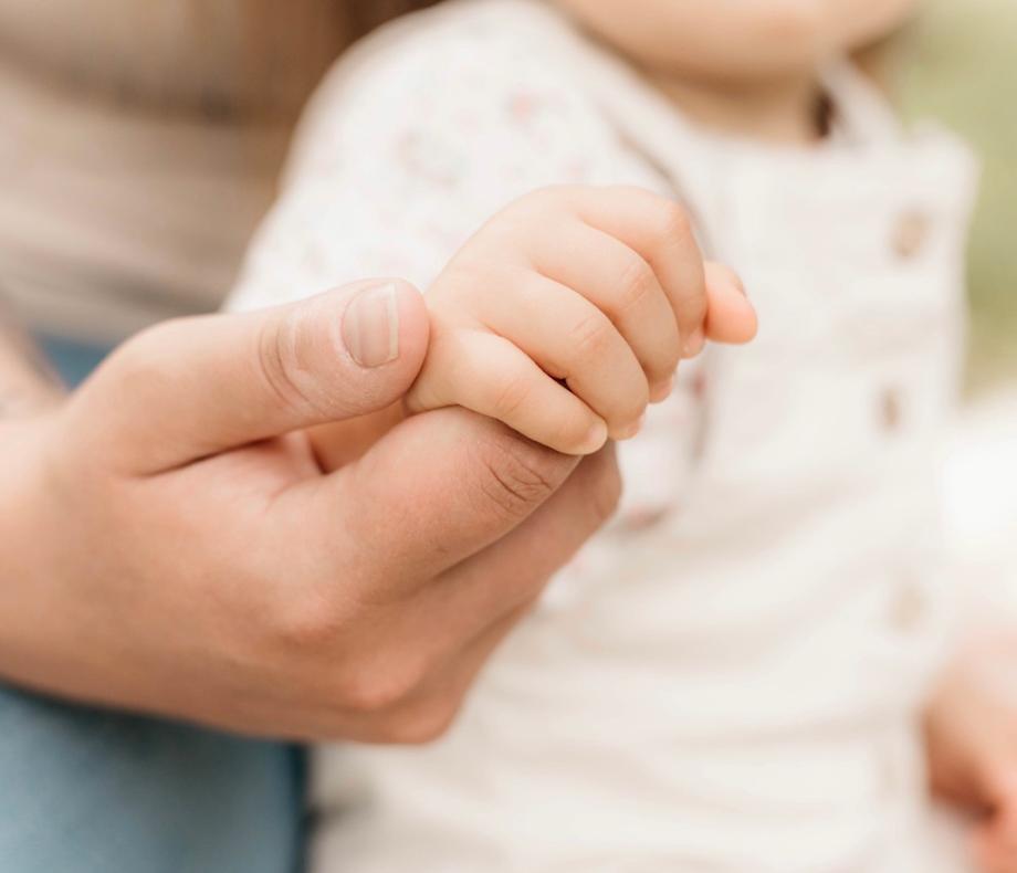 Babyhand umfasst den Finger eines Elternteils